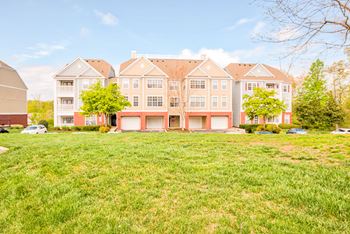 A large building with a red roof is surrounded by a green lawn.